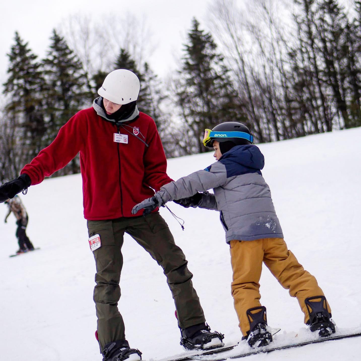 children in snowboarding lesson with instructor