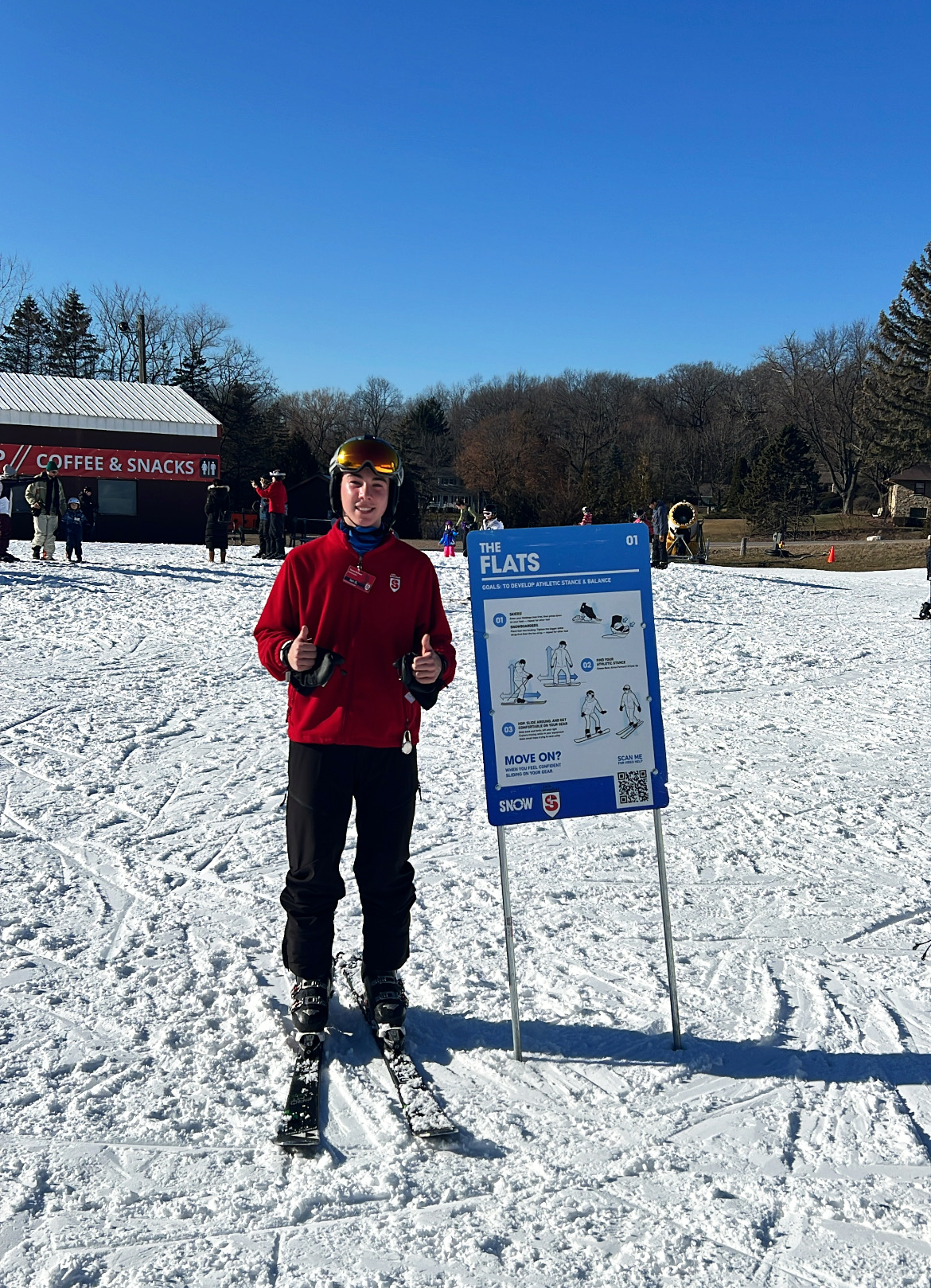 person on skis smiling next to terrain sign