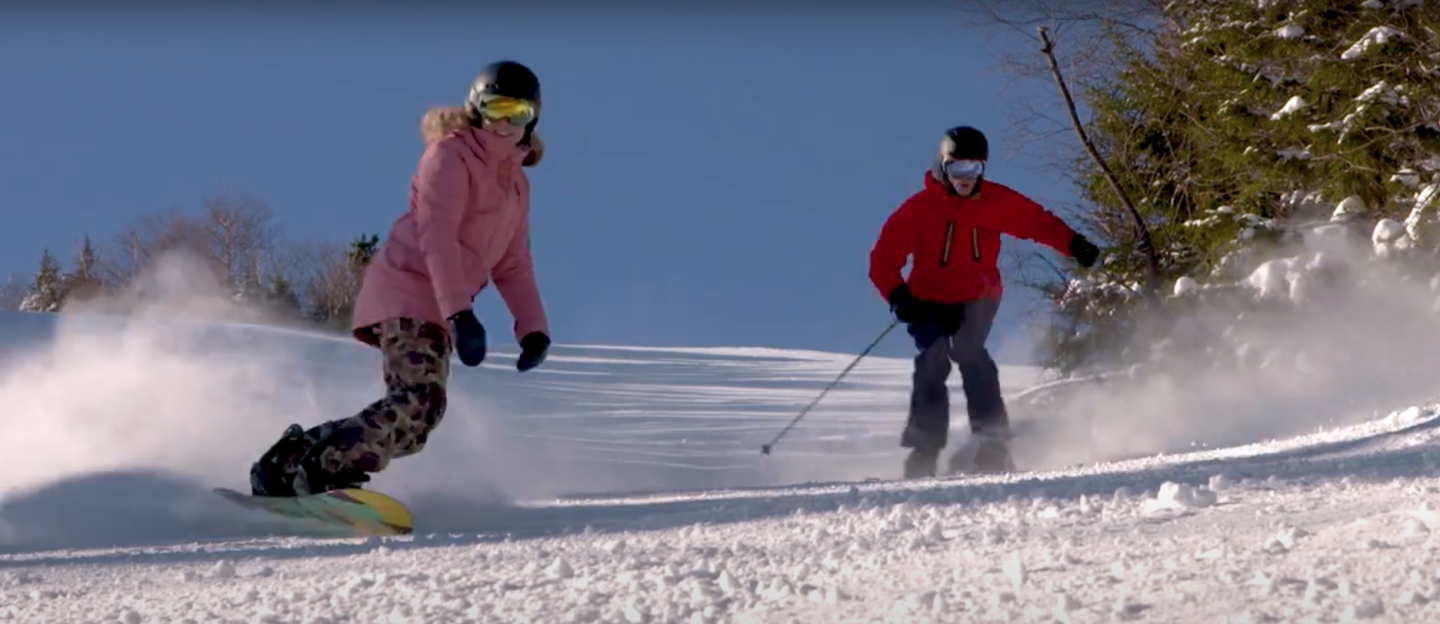 a pair of people skiing down hill