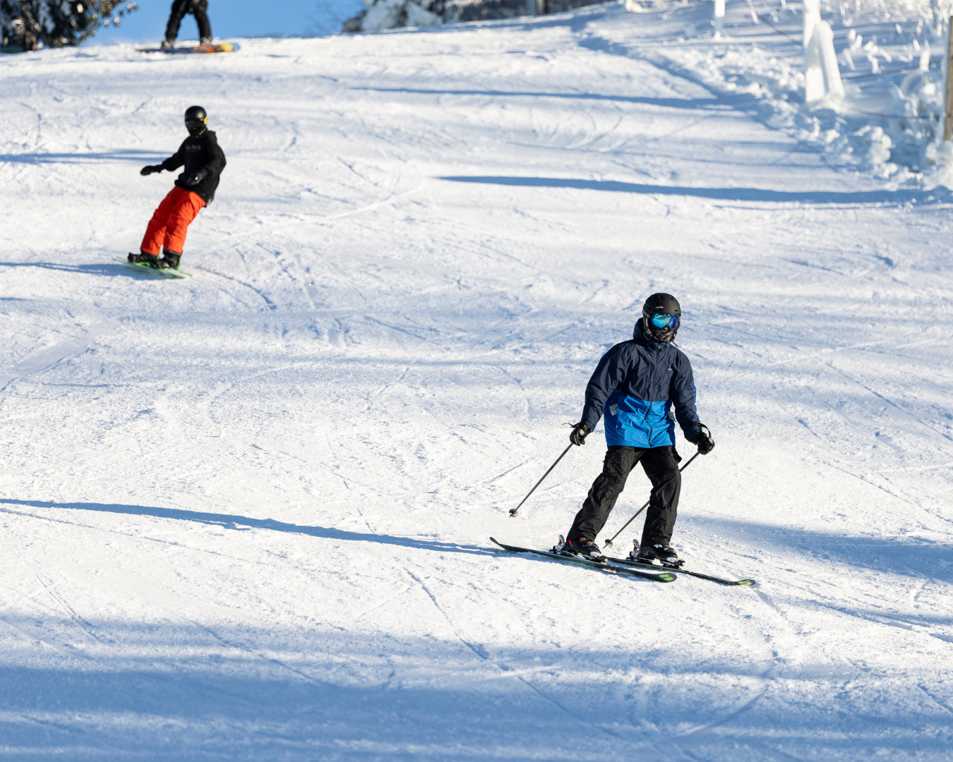 skier and snowboarder coming down hill