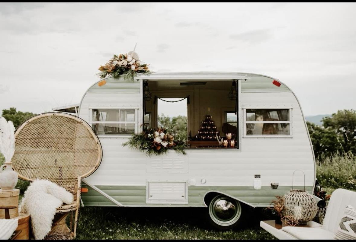 Vintage camper with floral decor under a cloudy sky.