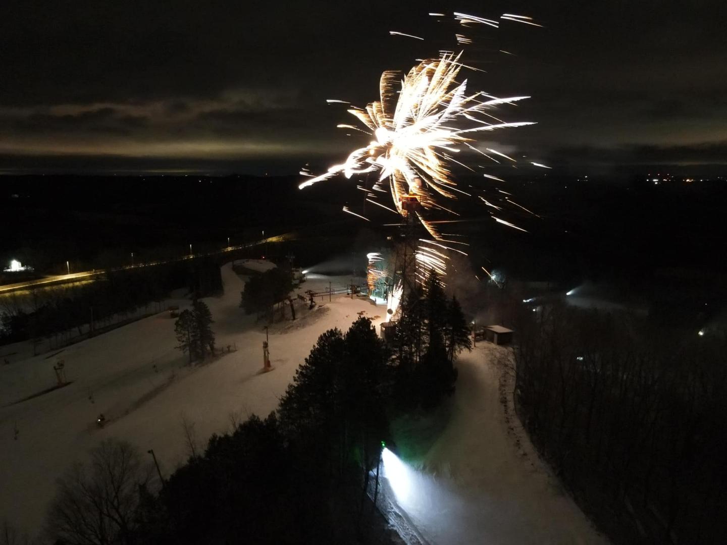 Fireworks light up the night sky over a snowy landscape.