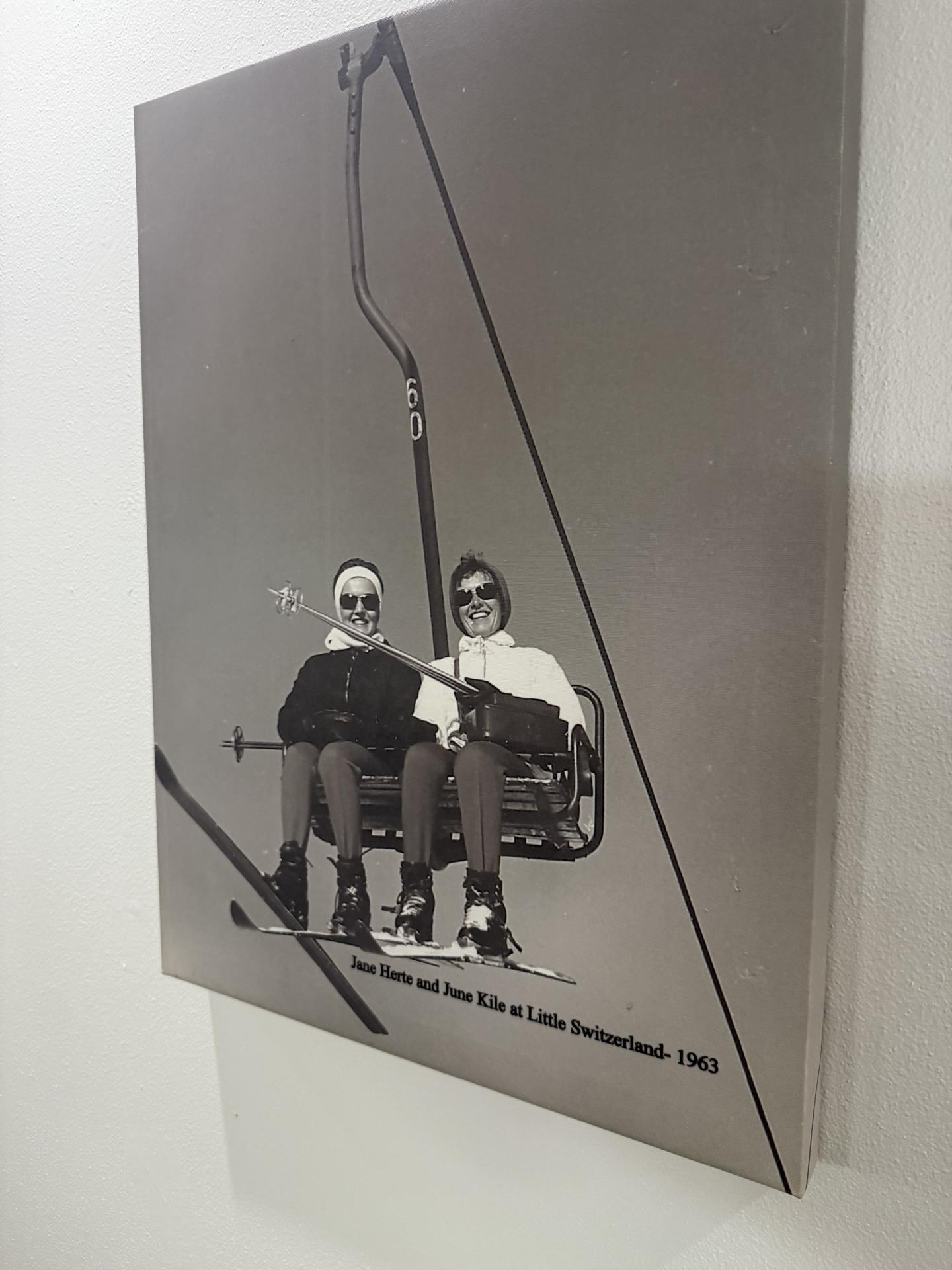 Two people on a ski lift in a vintage black and white photograph.