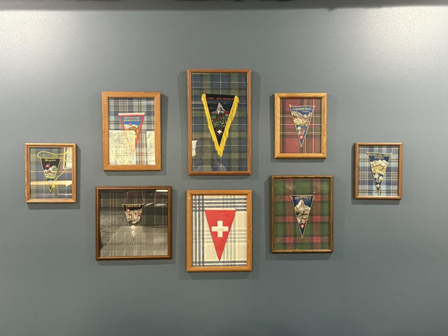 Framed patterned textiles on a gray wall, arranged in a grid.
