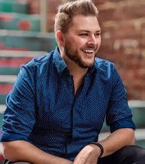 Smiling man in a blue shirt sitting on stairs.
