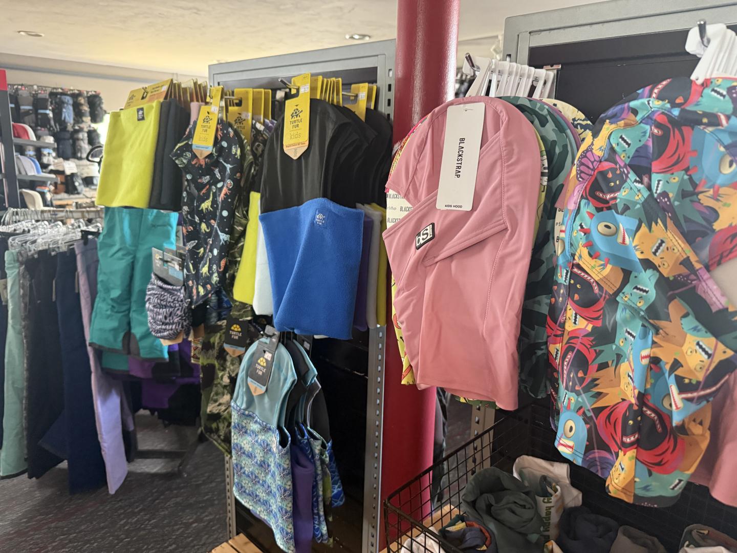Backpacks and clothing hang on racks in a store.