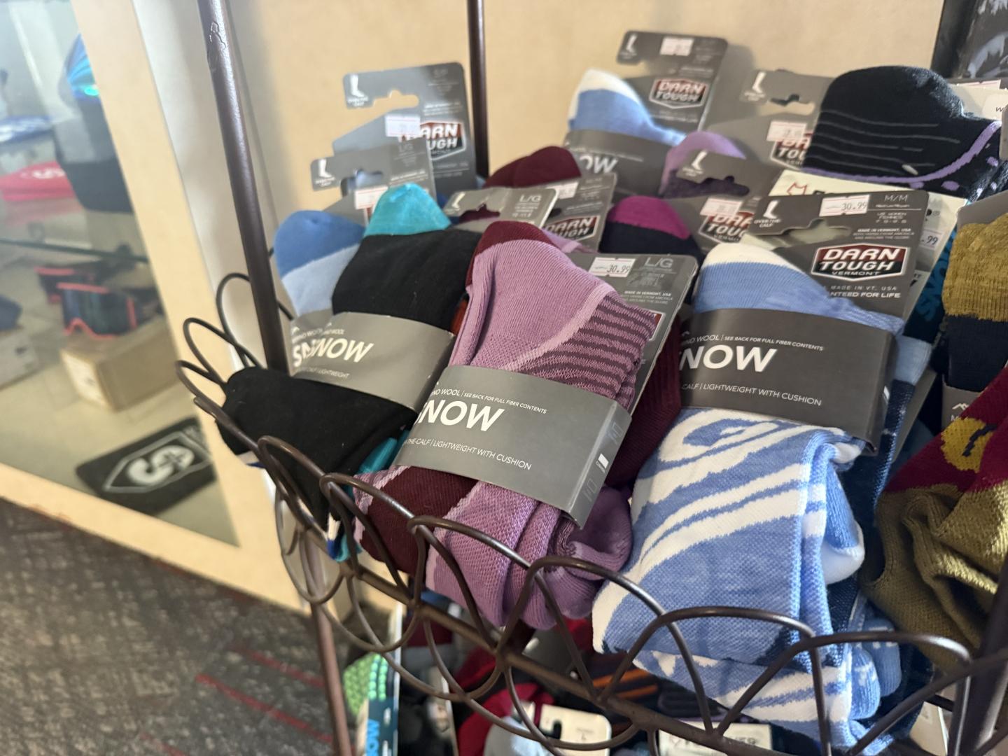 Colorful socks in a metal basket display in a store.