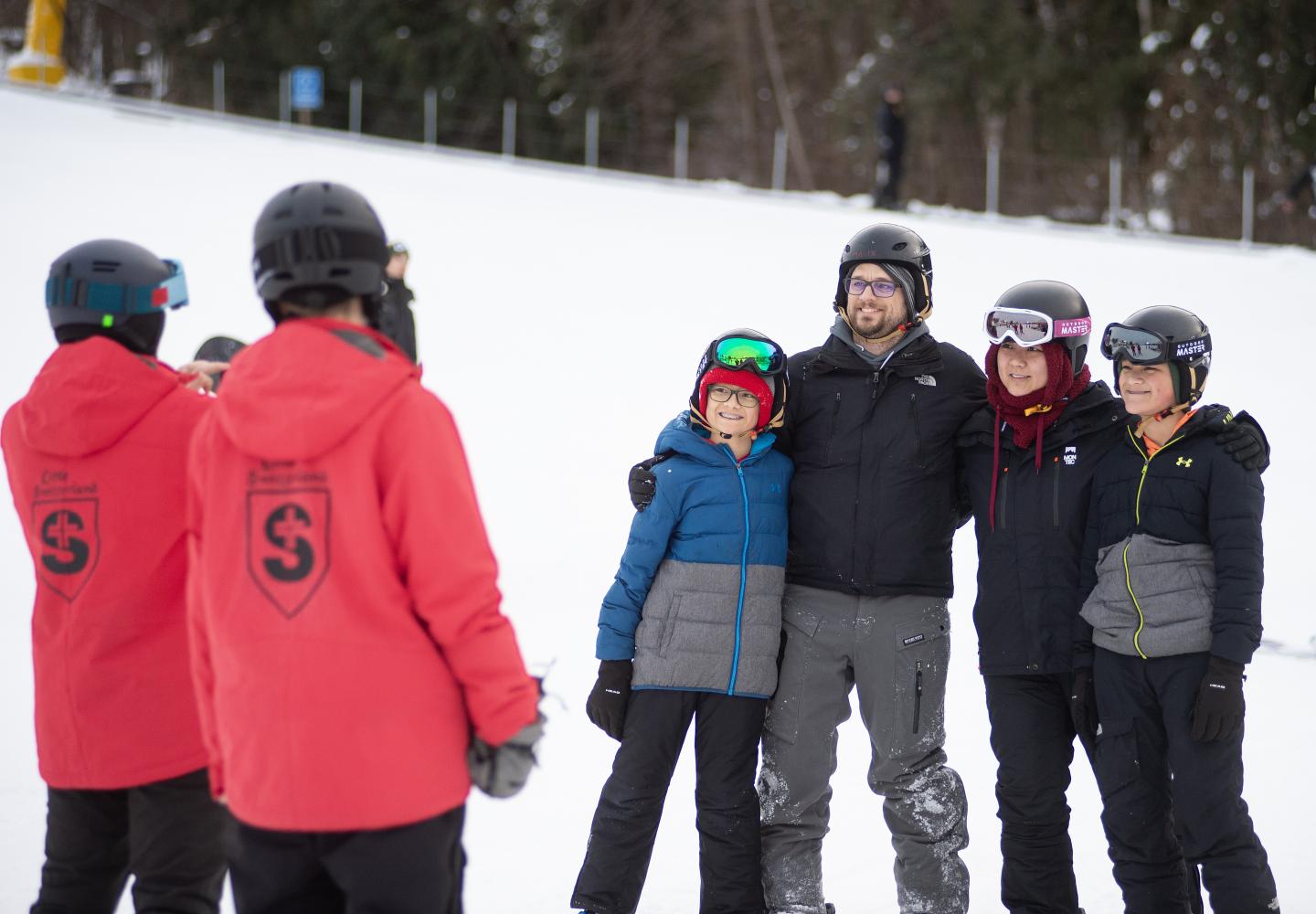 Family in snow gear posing for a photo on a snowy slope.