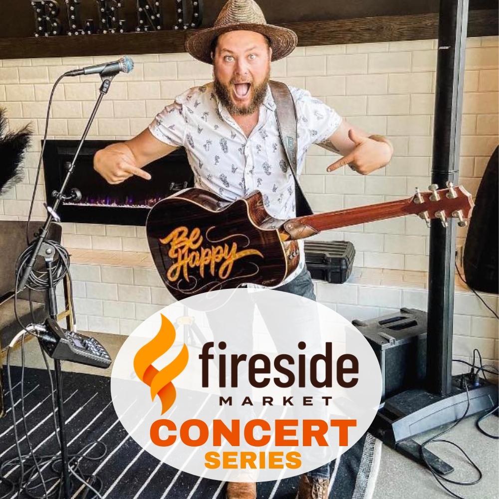 Musician with guitar smiling, pointing, and standing by microphones indoors.