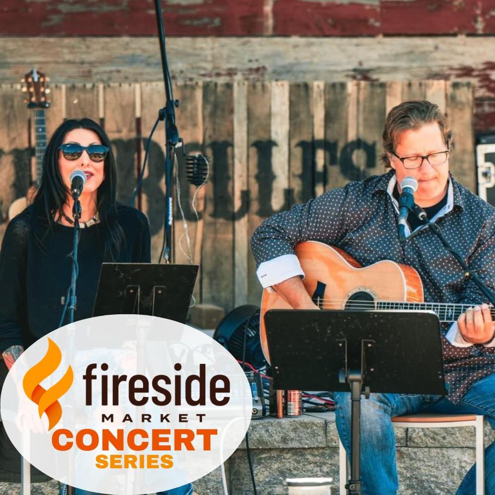 Singers perform at an outdoor concert with guitar and microphone.