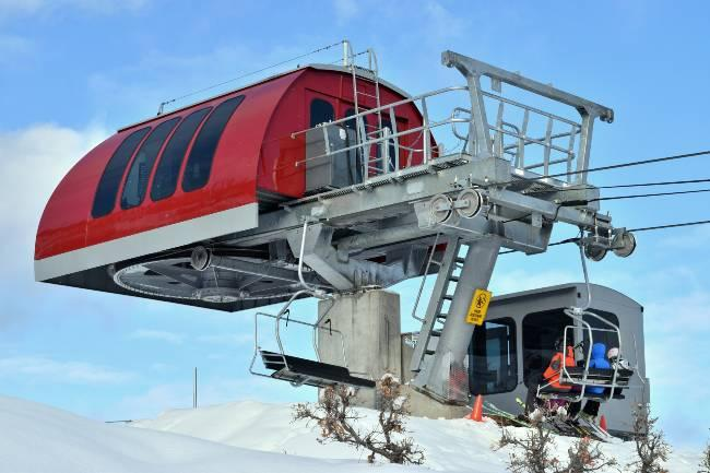 Red cable car station in snowy landscape under a clear blue sky.