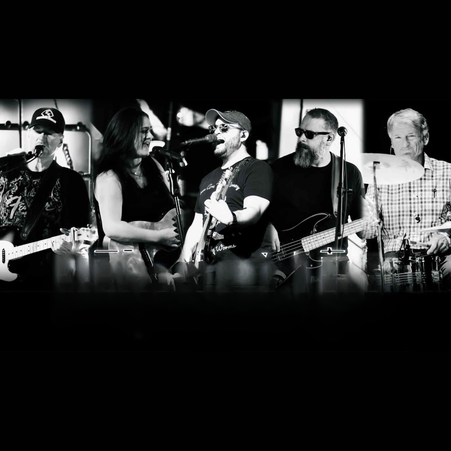 Musicians playing guitars and drums, in black and white.