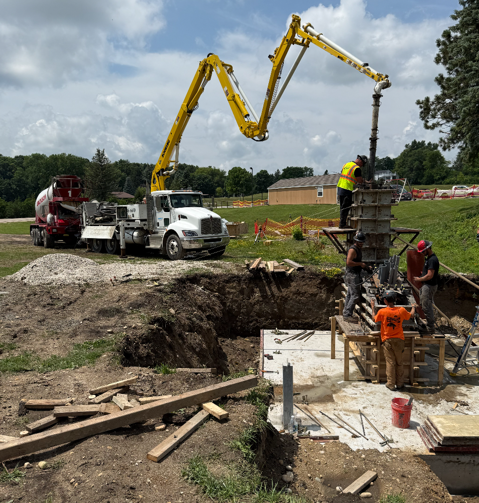 Construction site with workers and a yellow crane truck.