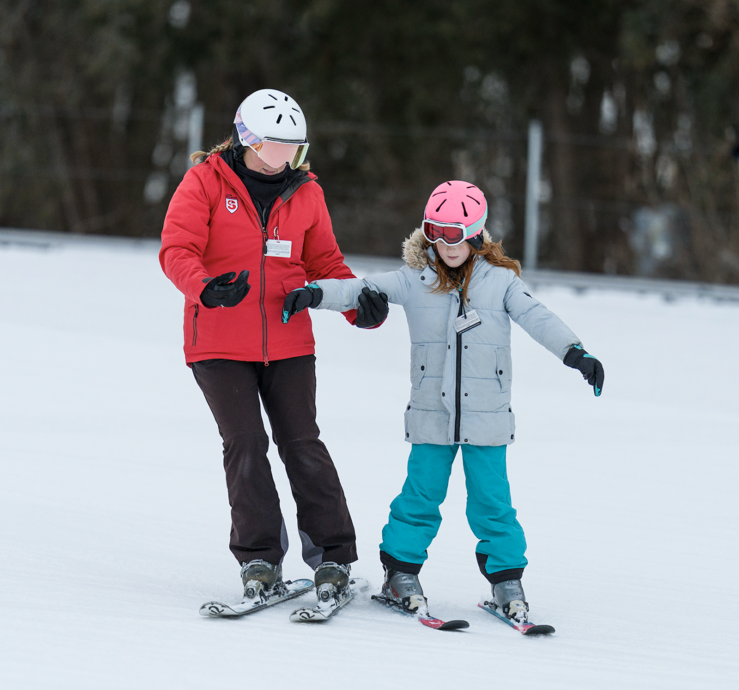 Adult and child skiing together on a snowy slope.