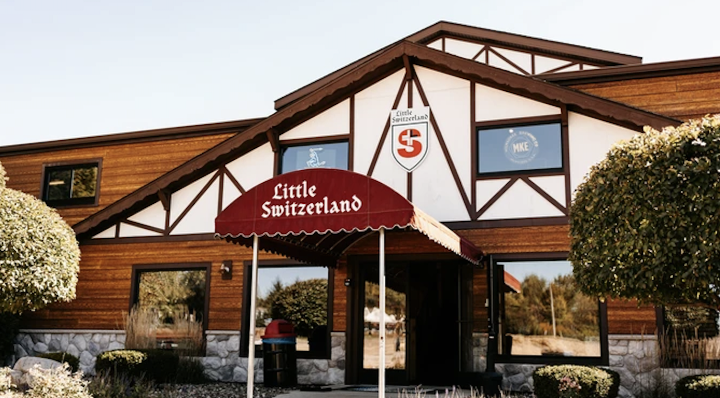 Rustic wooden café storefront with red awning and outdoor tables.