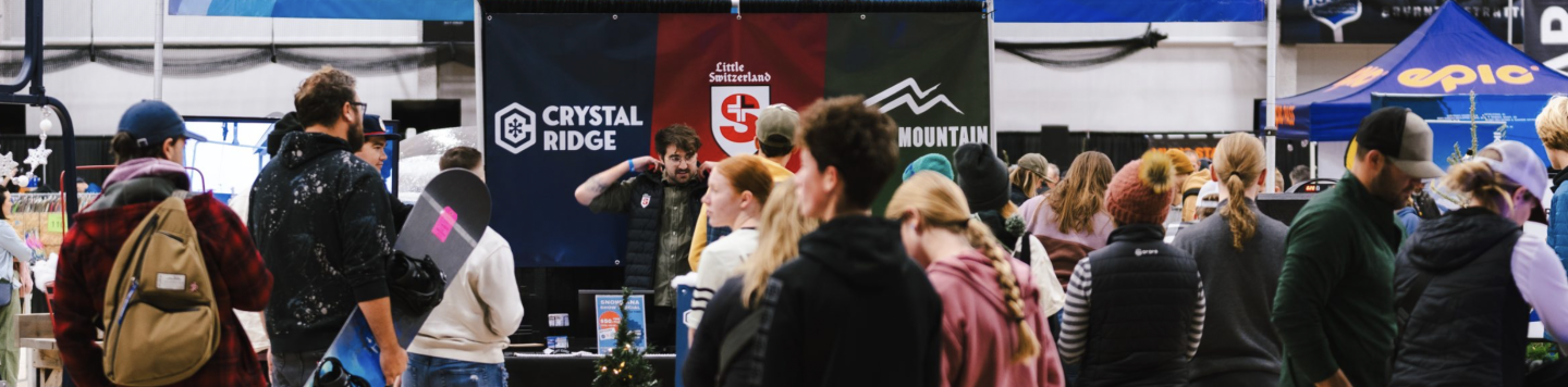 Crowded indoor tech expo with attendees gathered around booths.