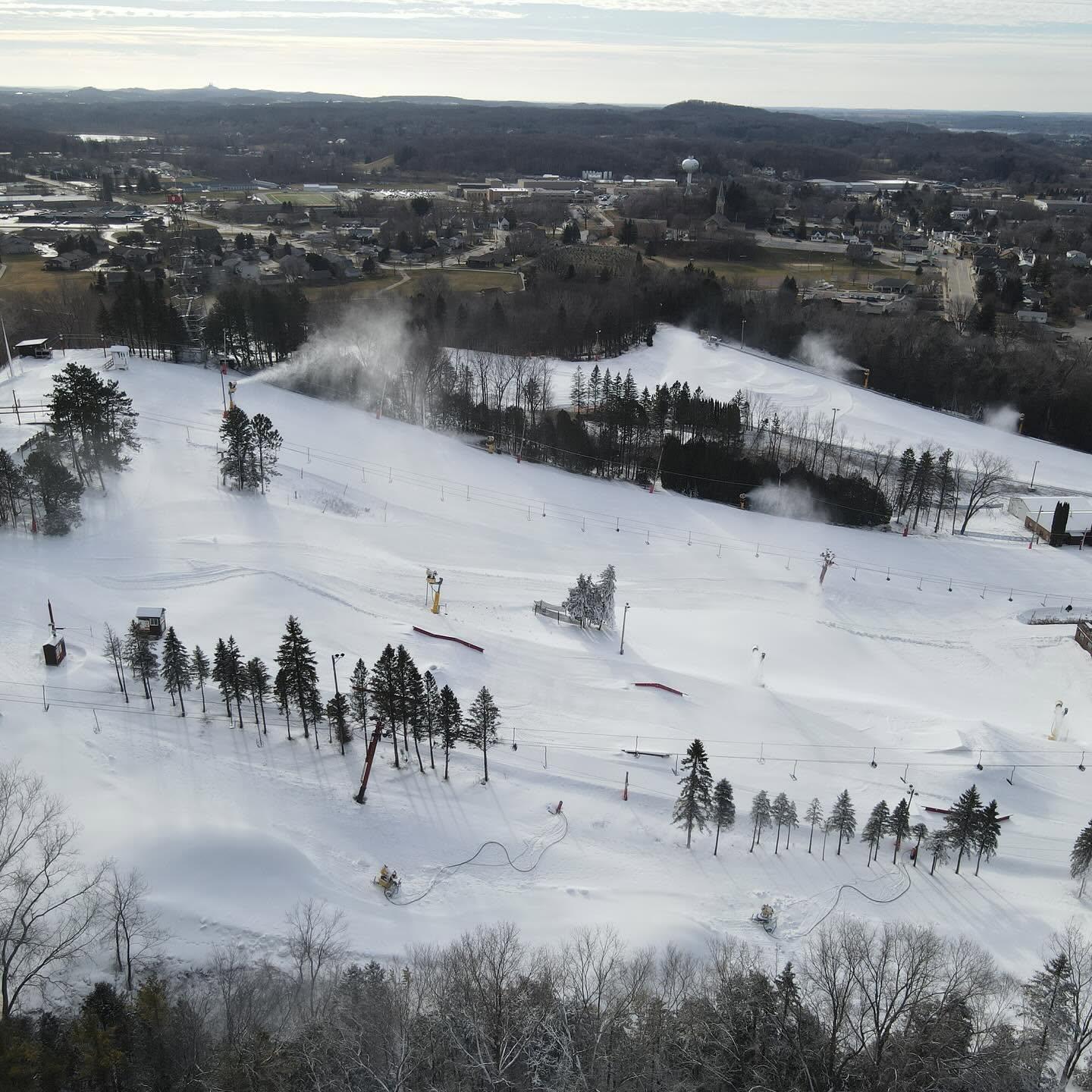 Aerial view of snow-covered ski slopes and tree-lined hills.