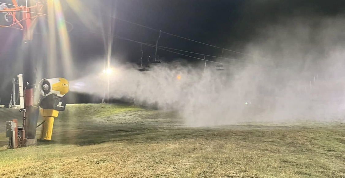 Nighttime field with a yellow irrigation cannon spraying a wide mist.